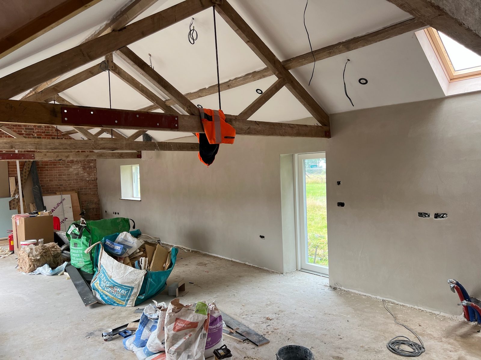 Internal plastering in a barn conversion with exposed oak trusses, Suffolk