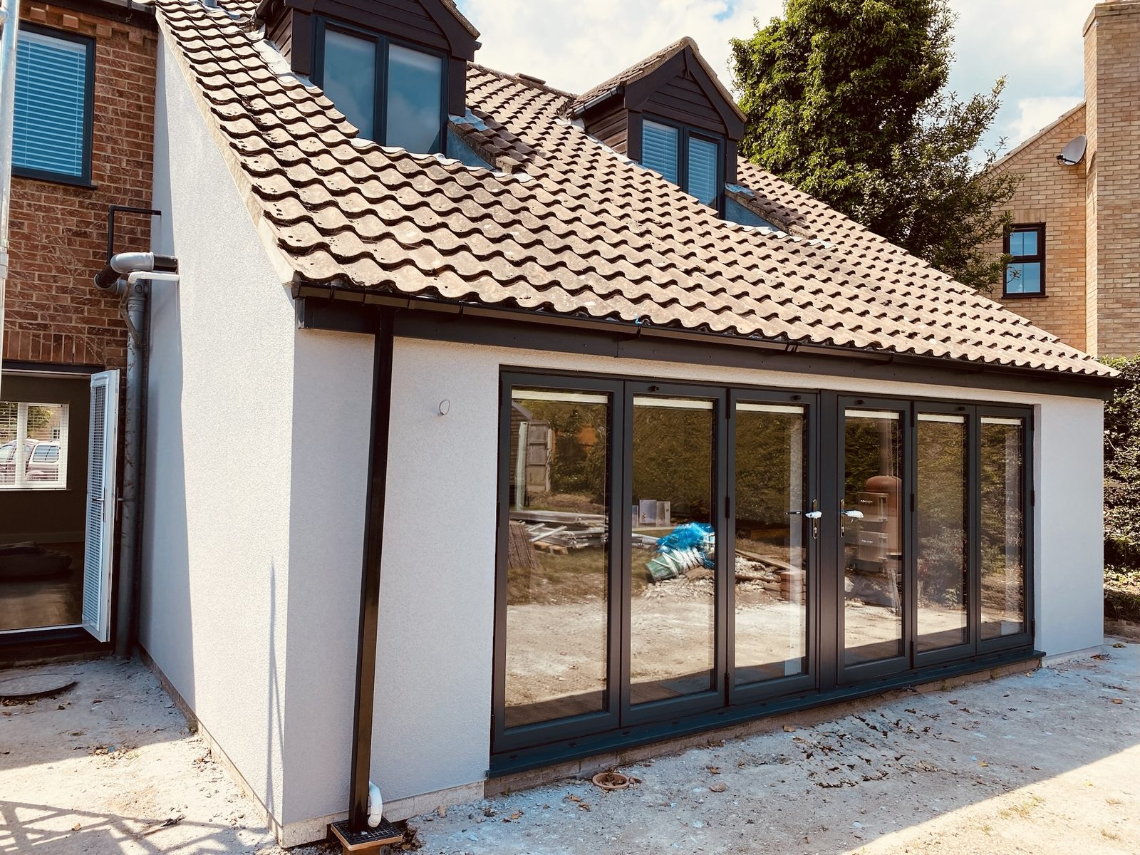 Freshly rendered single-storey extension with bifold doors by Morphey Plastering, Suffolk